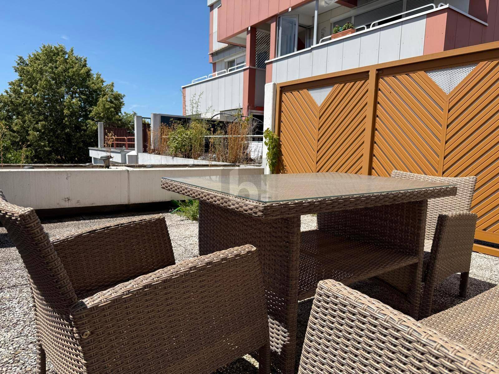 Geräumige Terrasse mit Rattanmöbeln und Blick auf die umliegenden Gebäude.