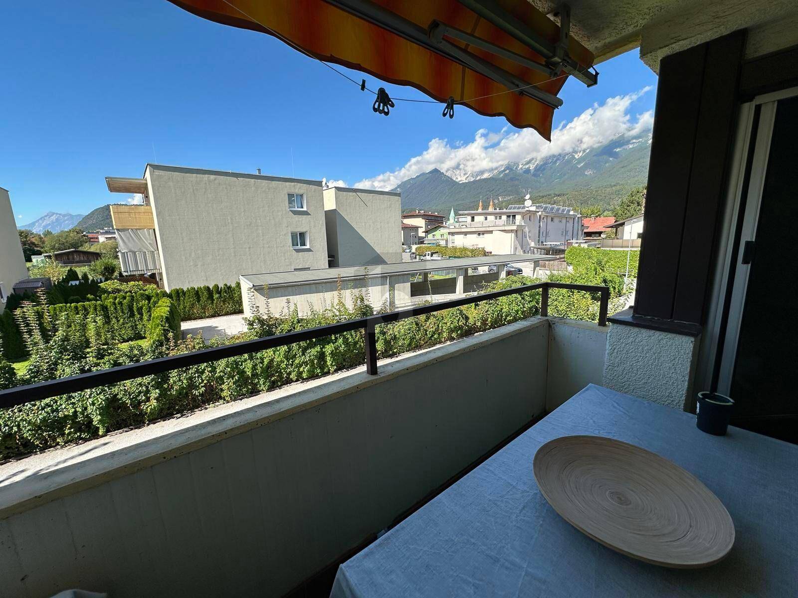 Sonniger Balkon mit Bergblick, Gartenmöbeln und Markise, ideal zum Entspannen im Freien.