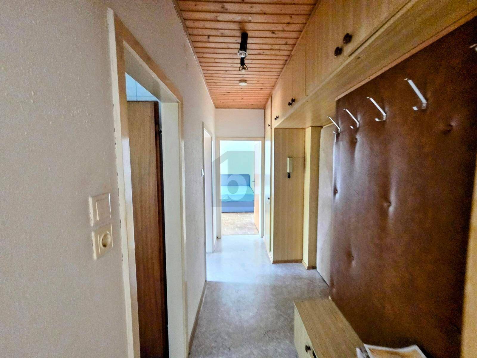 Flur mit Holzdecke, Einbauschränken und Garderobe, führt zu weiteren Räumen.