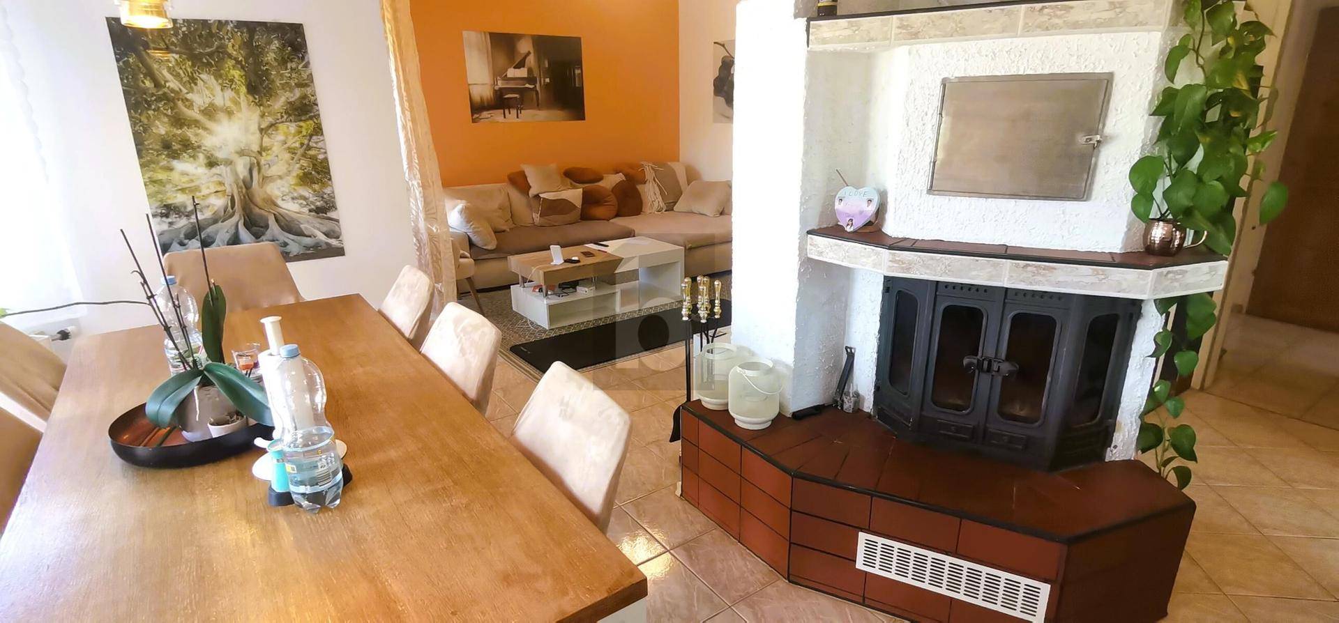 Gemütlicher Wohn-Essbereich mit Holztisch, Kamin und Sofa, ideal für gesellige Stunden.