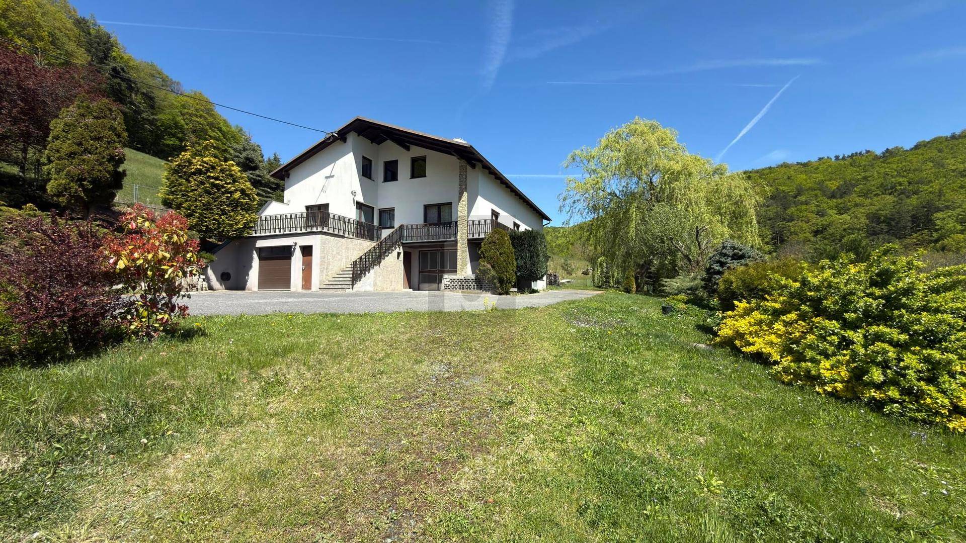 Freistehendes Haus mit weißer Fassade und großem Gartenbereich in ländlicher Umgebung.