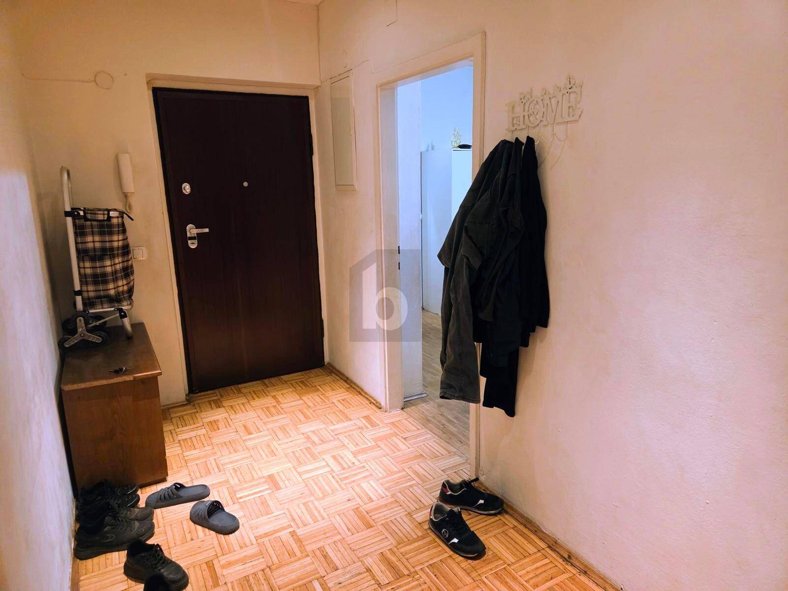Funktionaler Eingangsbereich mit Parkettboden und Garderobe, der zu weiteren Räumen führt.