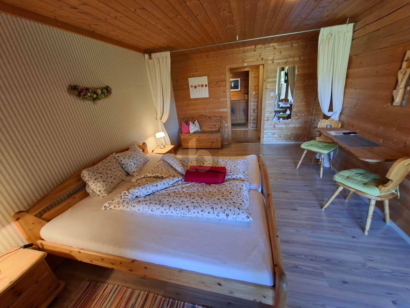 Rustikales Schlafzimmer mit Holzvertäfelung, zwei Einzelbetten und einem kleinen Arbeitsbereich.
