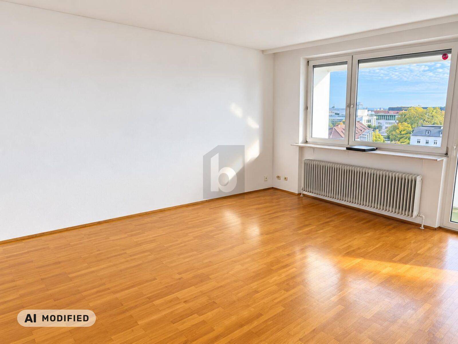 Geräumiges Zimmer mit hellem Parkettboden und großem Fenster, das viel Tageslicht hereinlässt.