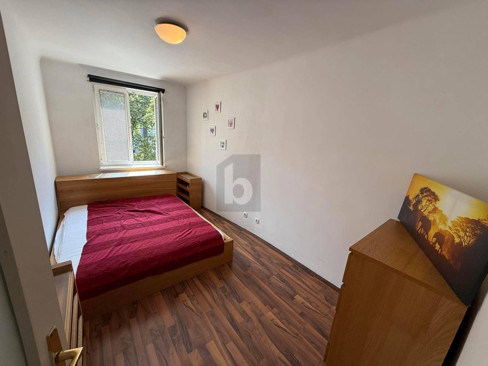 Gemütliches Schlafzimmer mit Einzelbett, Holzmöbeln und Fensterblick ins Grüne.