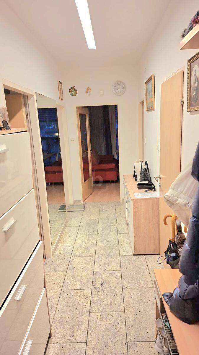 Heller Flur mit Fliesenboden, Spiegel und Kommode, der zu weiteren Räumen der Wohnung führt.