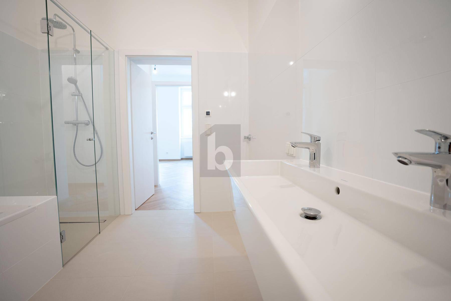 Modernes Badezimmer mit Doppelwaschbecken, großer begehbarer Dusche und weißen Fliesen.