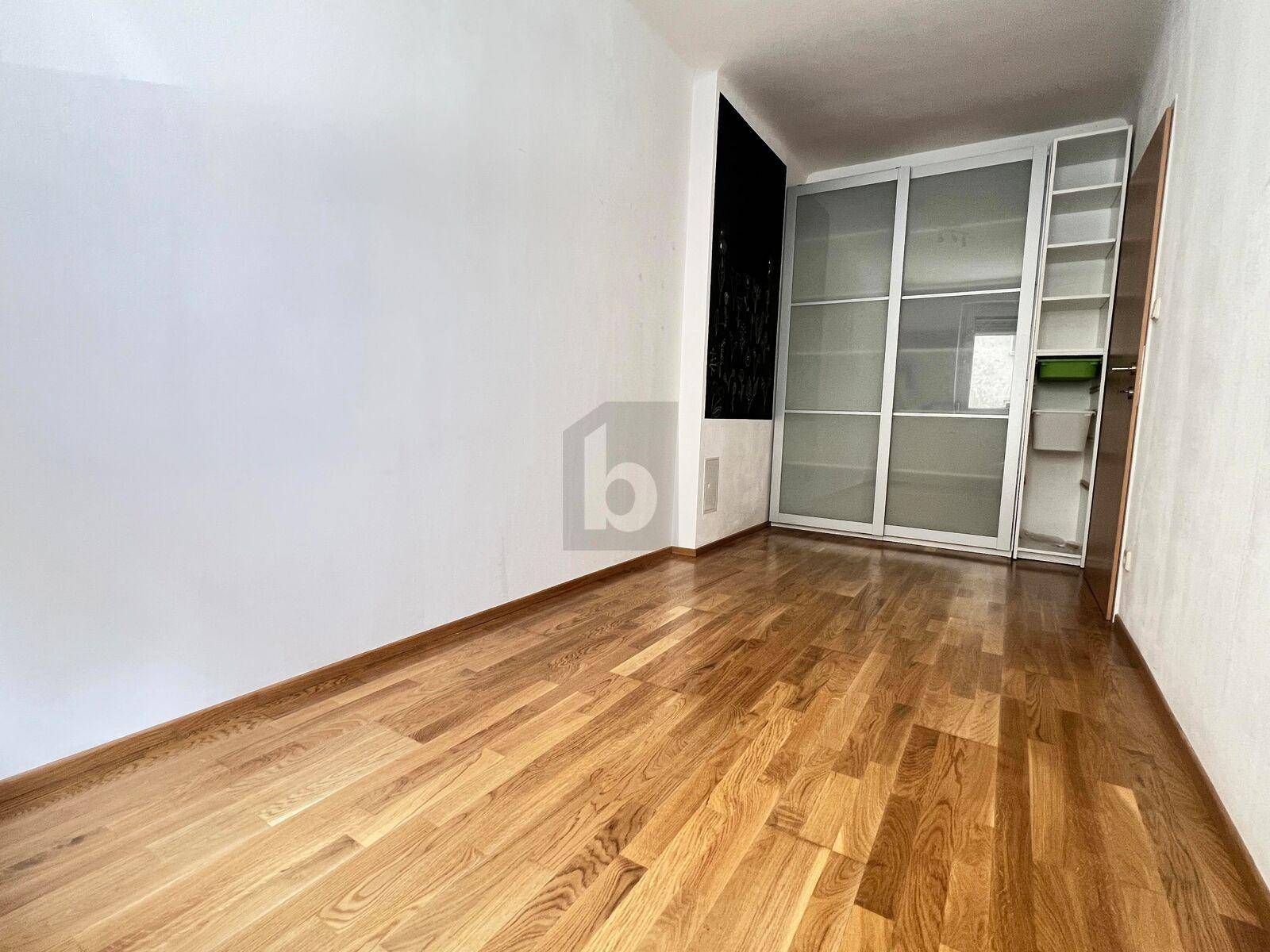 Leeres Zimmer mit hellem Parkettboden und großem Einbauschrank mit Schiebetüren.