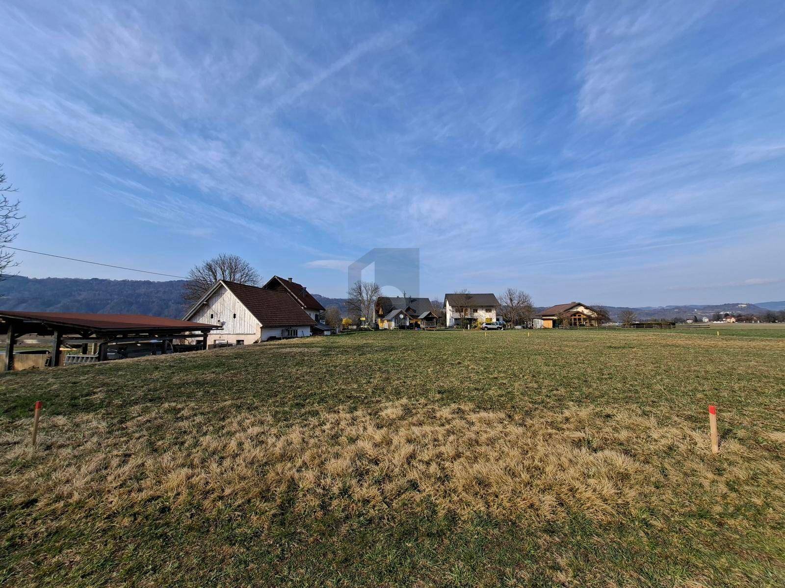 Ländliche Szenerie mit einem großen Feld, umgeben von Häusern und einer Bergkette.