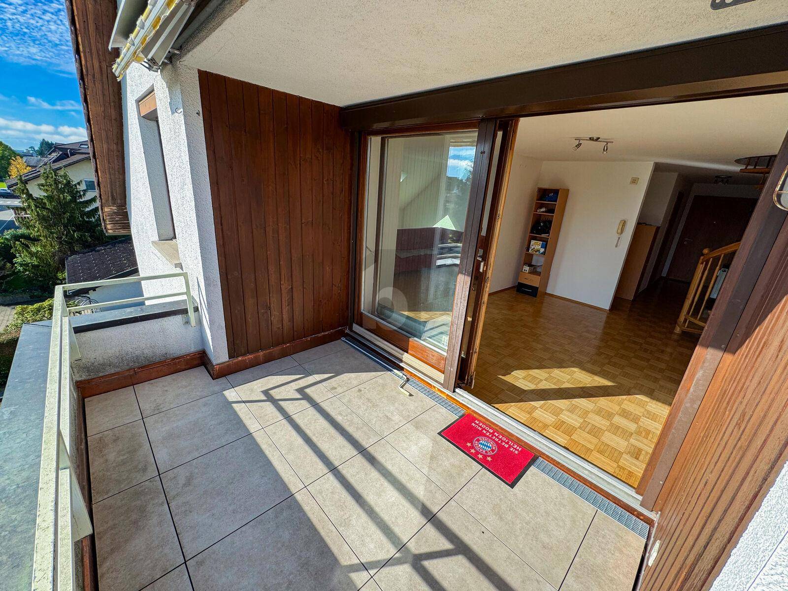Gefliester Balkon mit Holzwänden und Blick auf die Umgebung, zugänglich vom Wohnbereich.