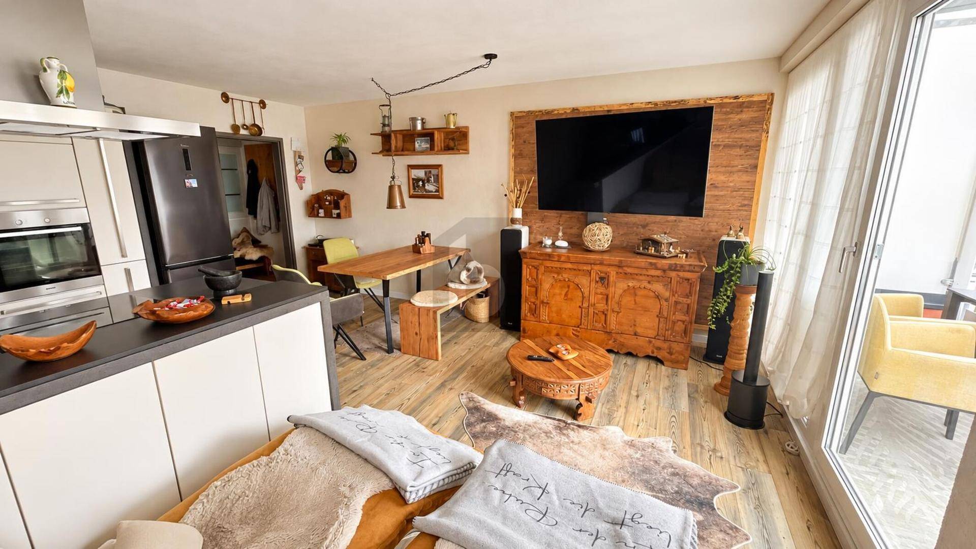 Heller offener Wohn- und Essbereich mit moderner Küche, Holzelementen und großzügigem Zugang zur Terrasse.