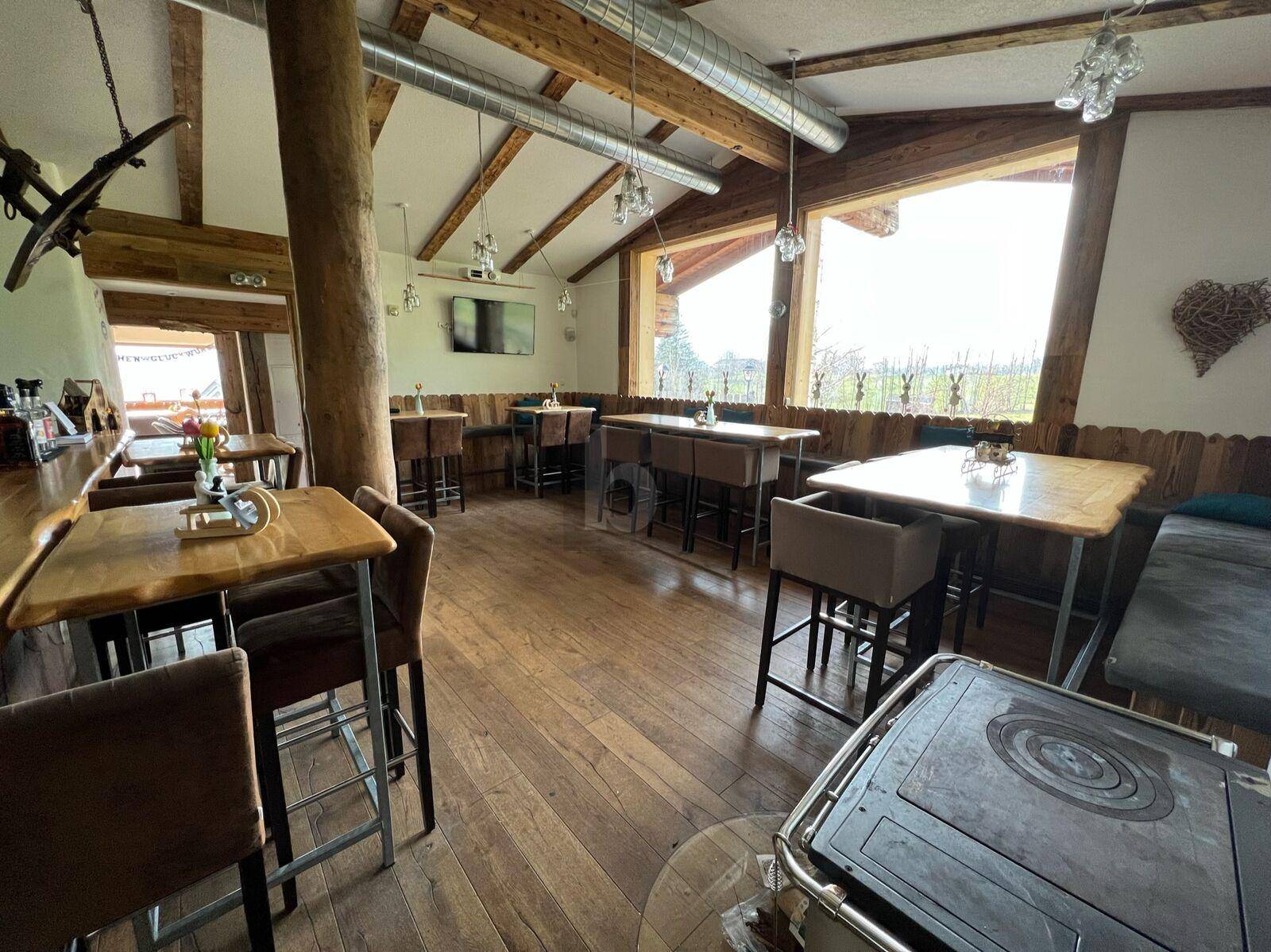 Rustikaler Gastraum mit Holzböden, hohen Decken und einer Bar, ideal für gesellige Runden.