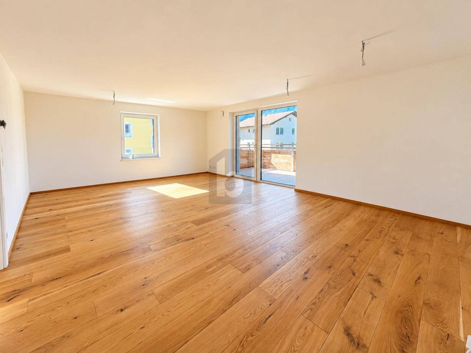 Geräumiger, heller Raum mit Holzboden und großen Schiebetüren zum Außenbereich.