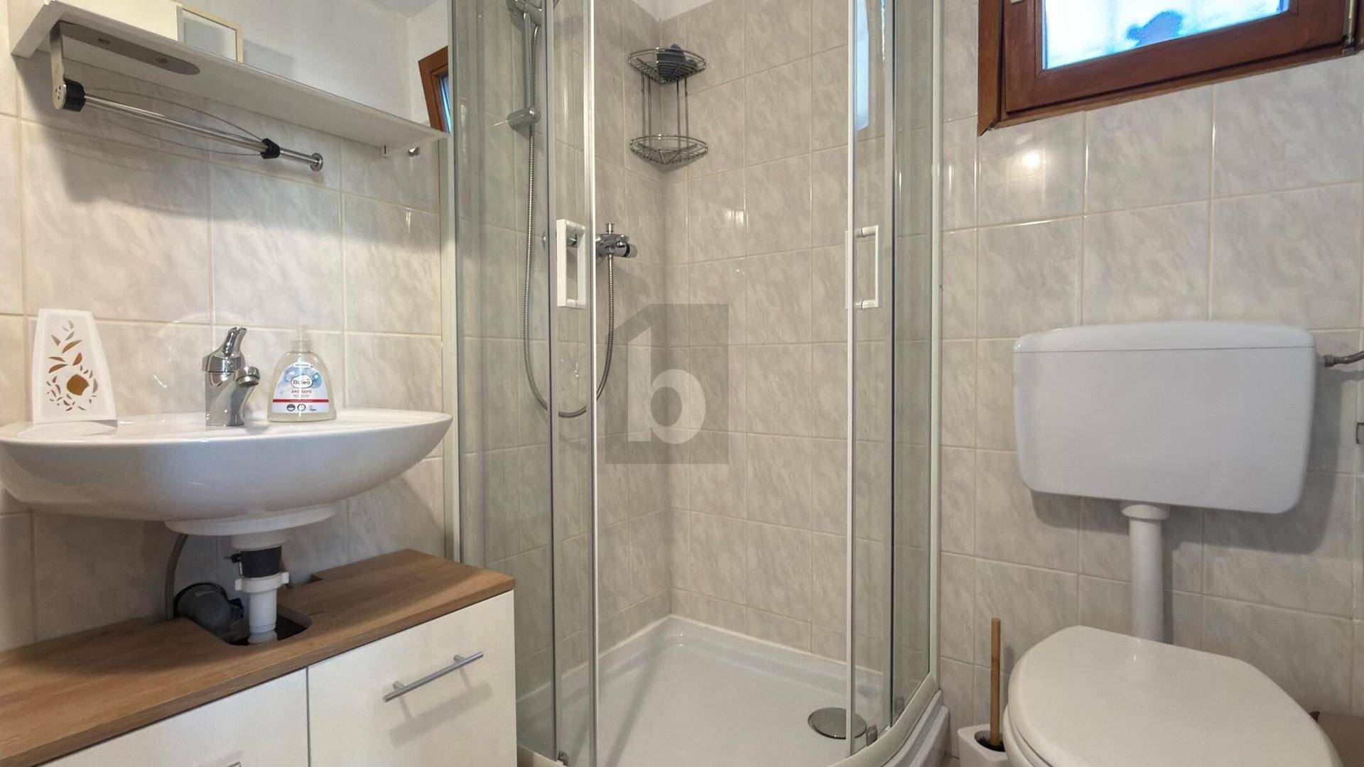 Helles Badezimmer mit Duschkabine, Waschbecken und WC, ausgestattet mit Fenster.