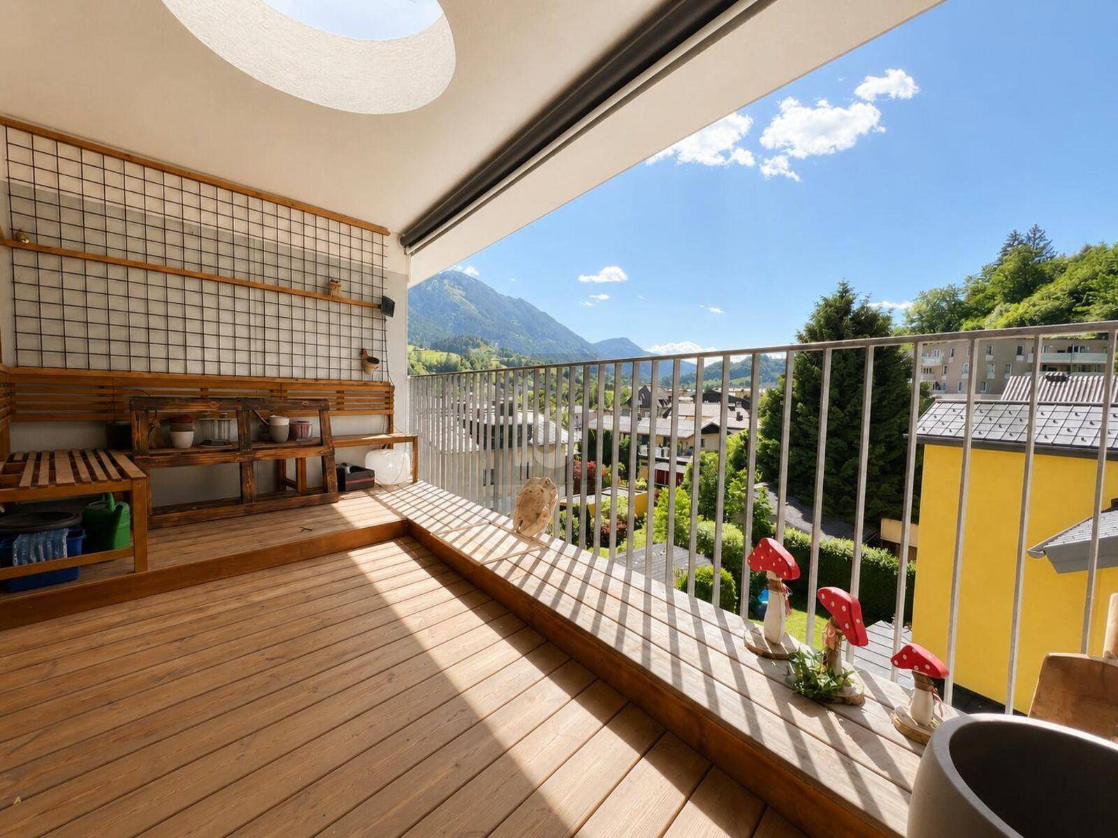 Sonniger Balkon mit Holzboden, Sitzgelegenheiten und weitem Bergblick.
