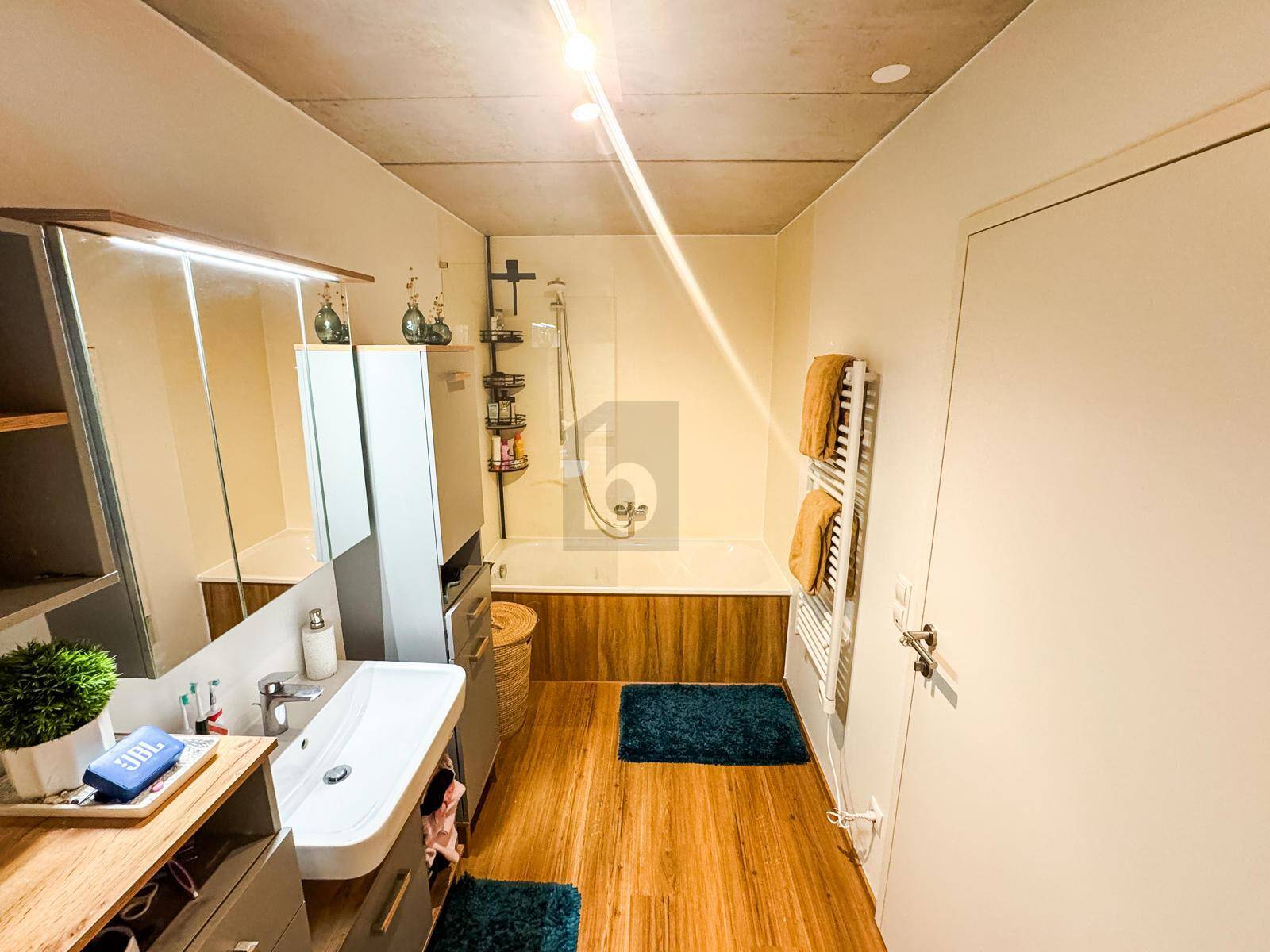 Modernes Badezimmer mit Badewanne, Einzelwaschbecken und beheiztem Handtuchhalter.