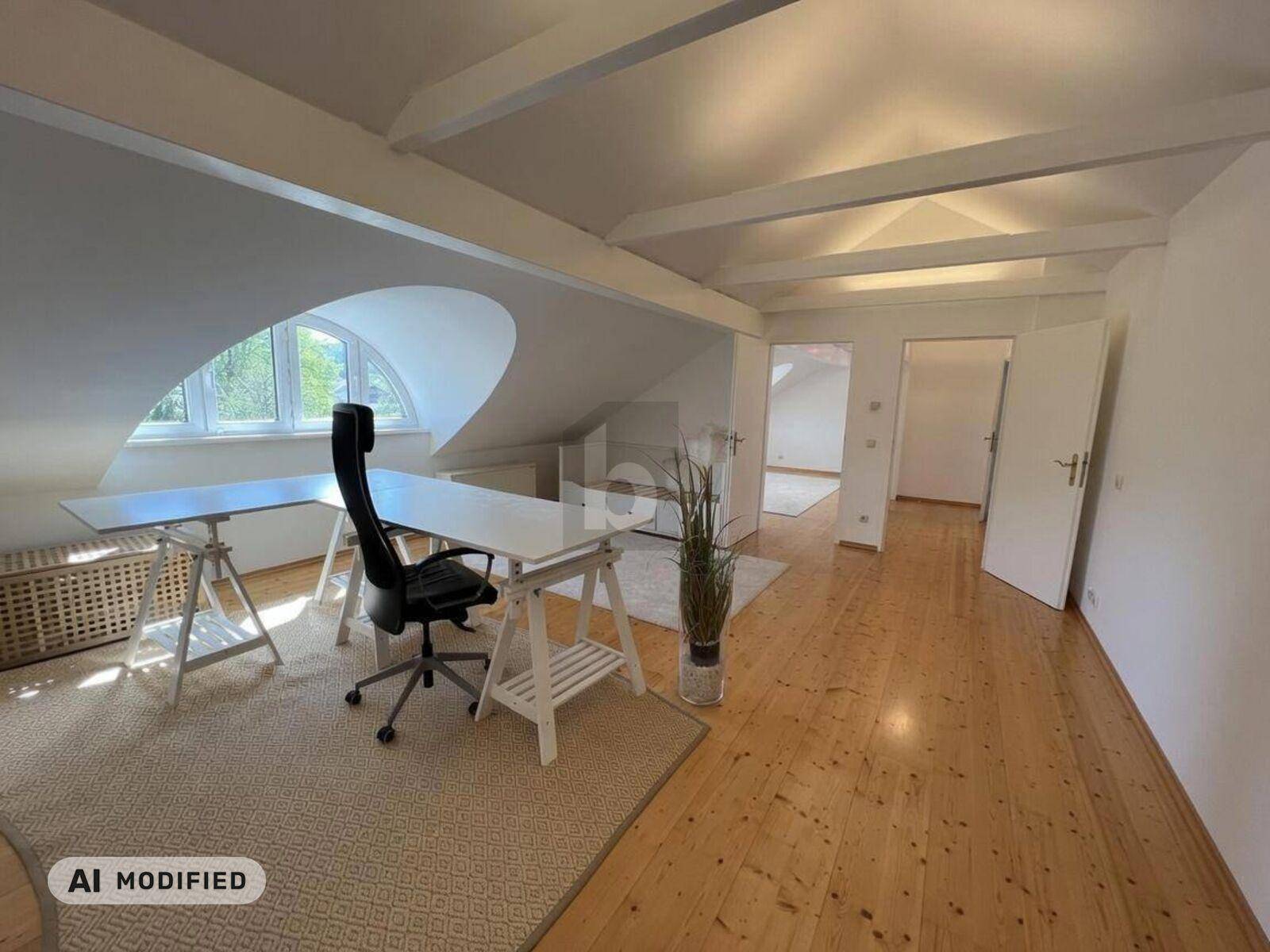 Helles Dachzimmer, als Büro eingerichtet, mit Holzboden und sichtbaren Deckenbalken.