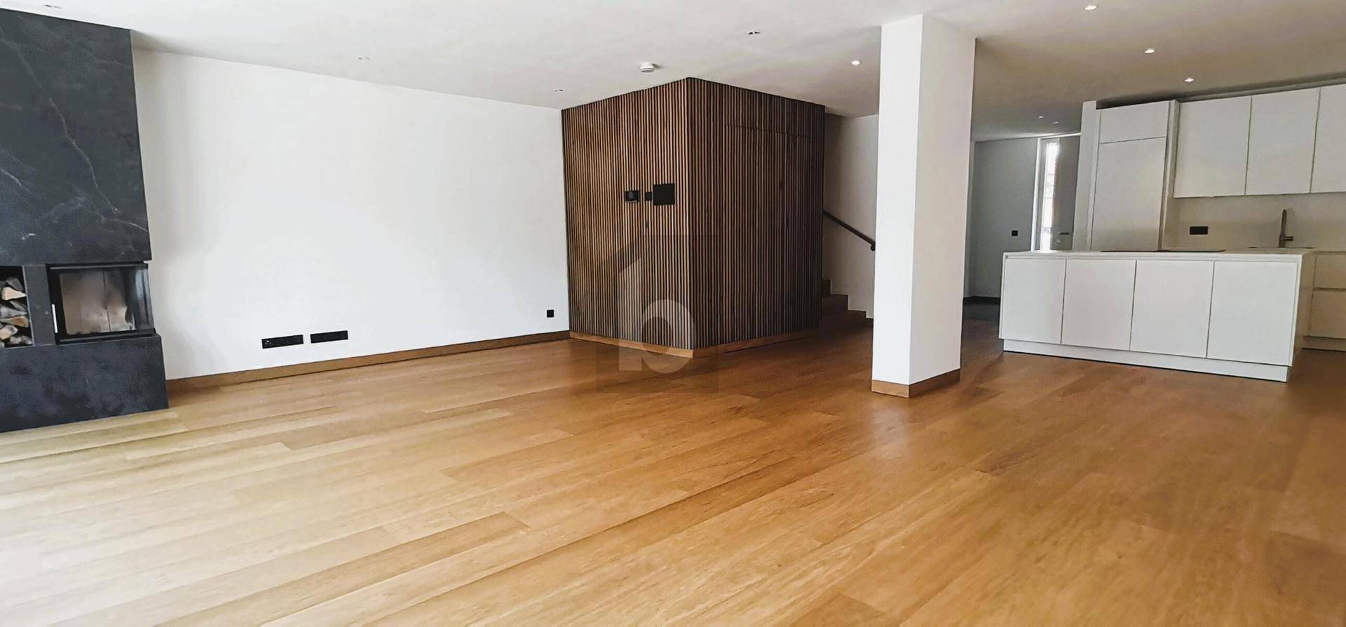 Heller offener Wohnbereich mit Kamin, Holzfußboden und angrenzender moderner Küche.