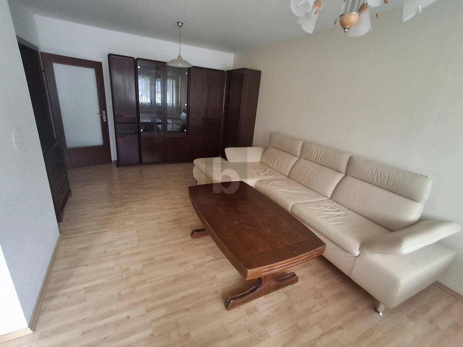Helles Wohnzimmer mit beigem Sofa, Holztisch und Parkettboden.