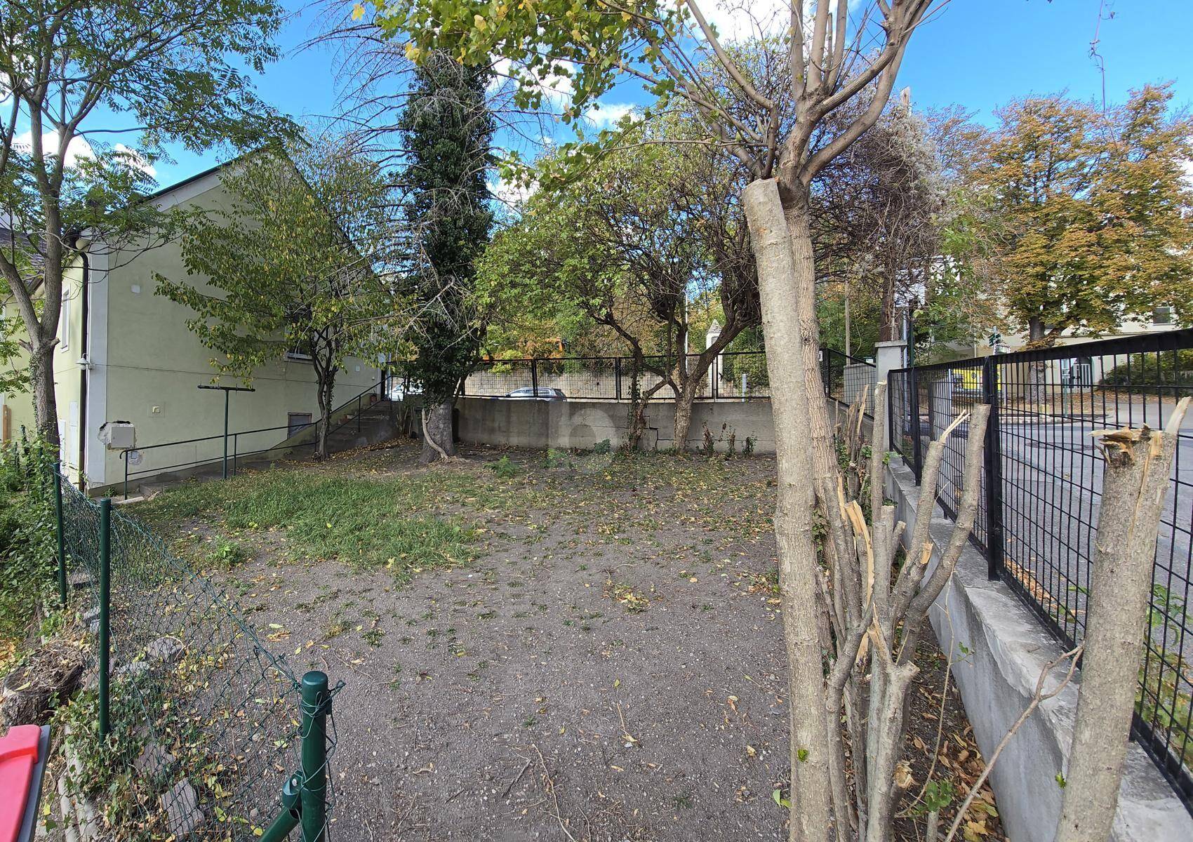 Grundstück neben dem Haus mit Bäumen, Gras und Zaun, ideal für einen Garten.