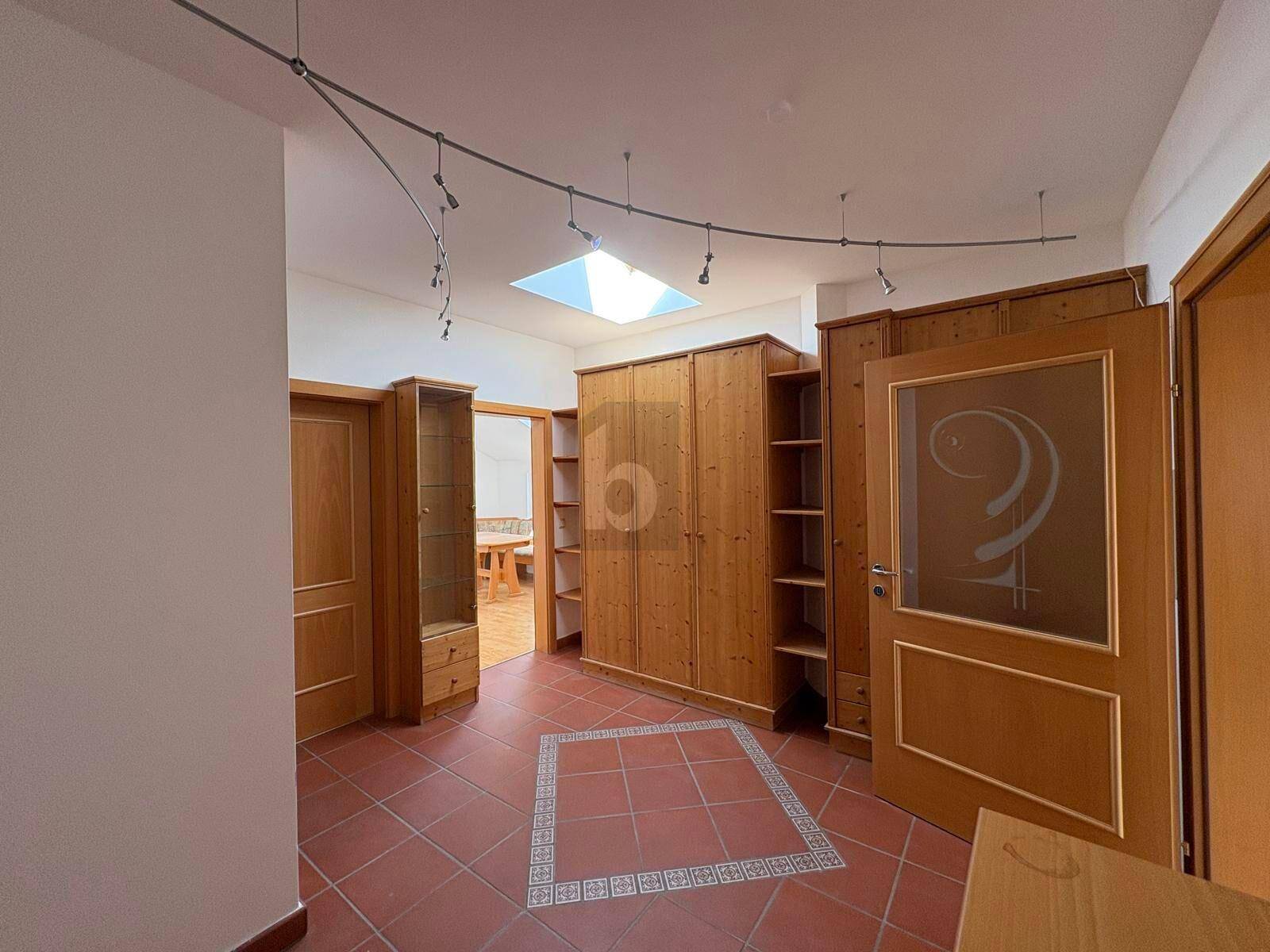 Flur mit Holzschränken, Terrakotta-Fliesenboden und einem Oberlicht für natürliches Licht.
