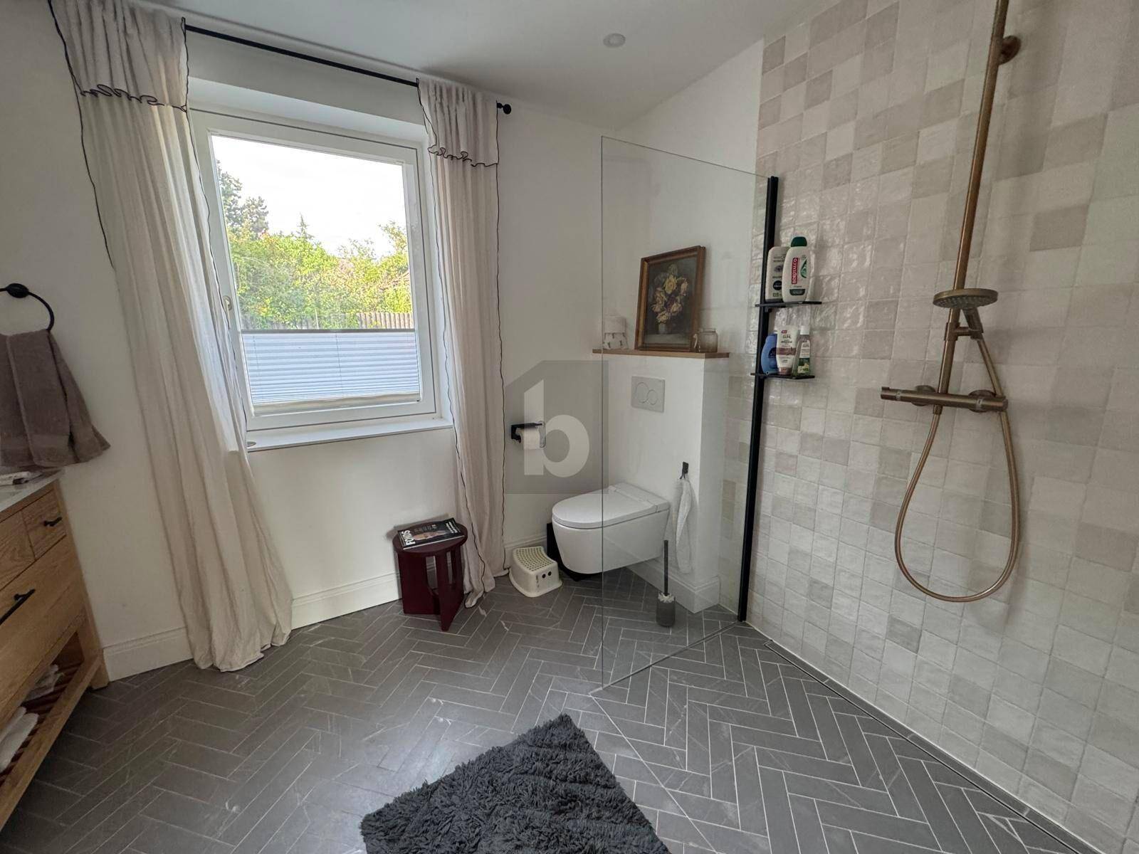 Modernes Badezimmer mit ebenerdiger Dusche, Wand-WC und Fenster für Tageslicht.