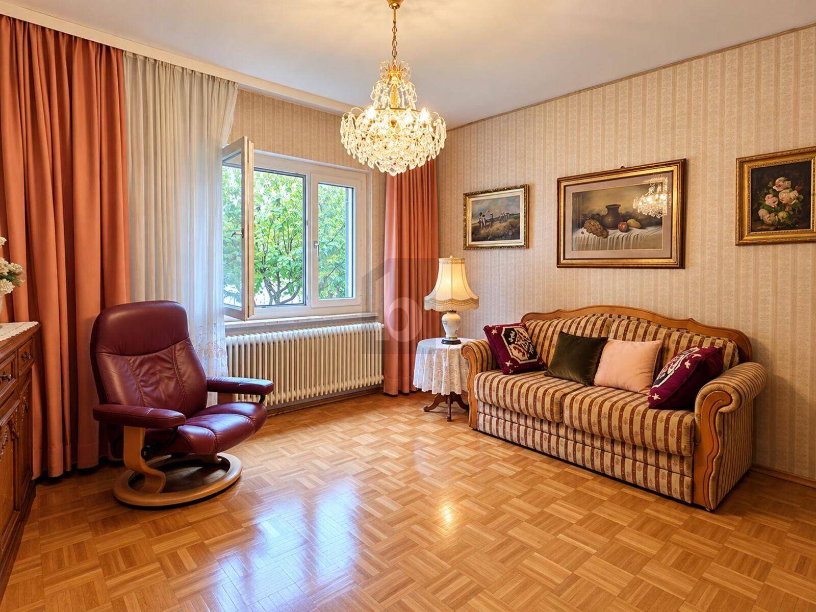 Gemütliches Wohnzimmer mit klassischem Parkettboden, bequemer Couch und einem eleganten Kronleuchter.