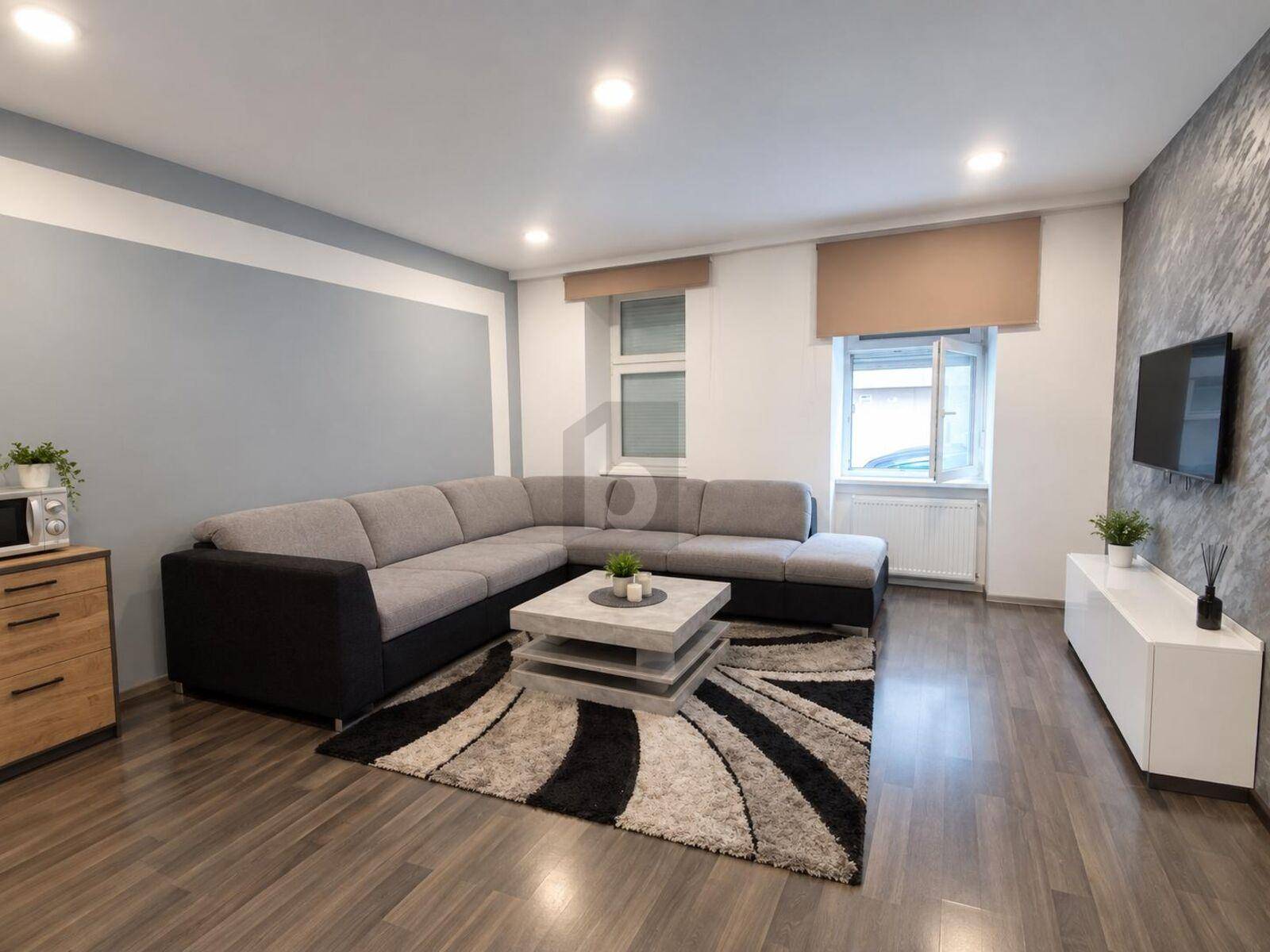 Gemütliches Wohnzimmer mit großem Ecksofa, modernem Couchtisch und Laminatboden.