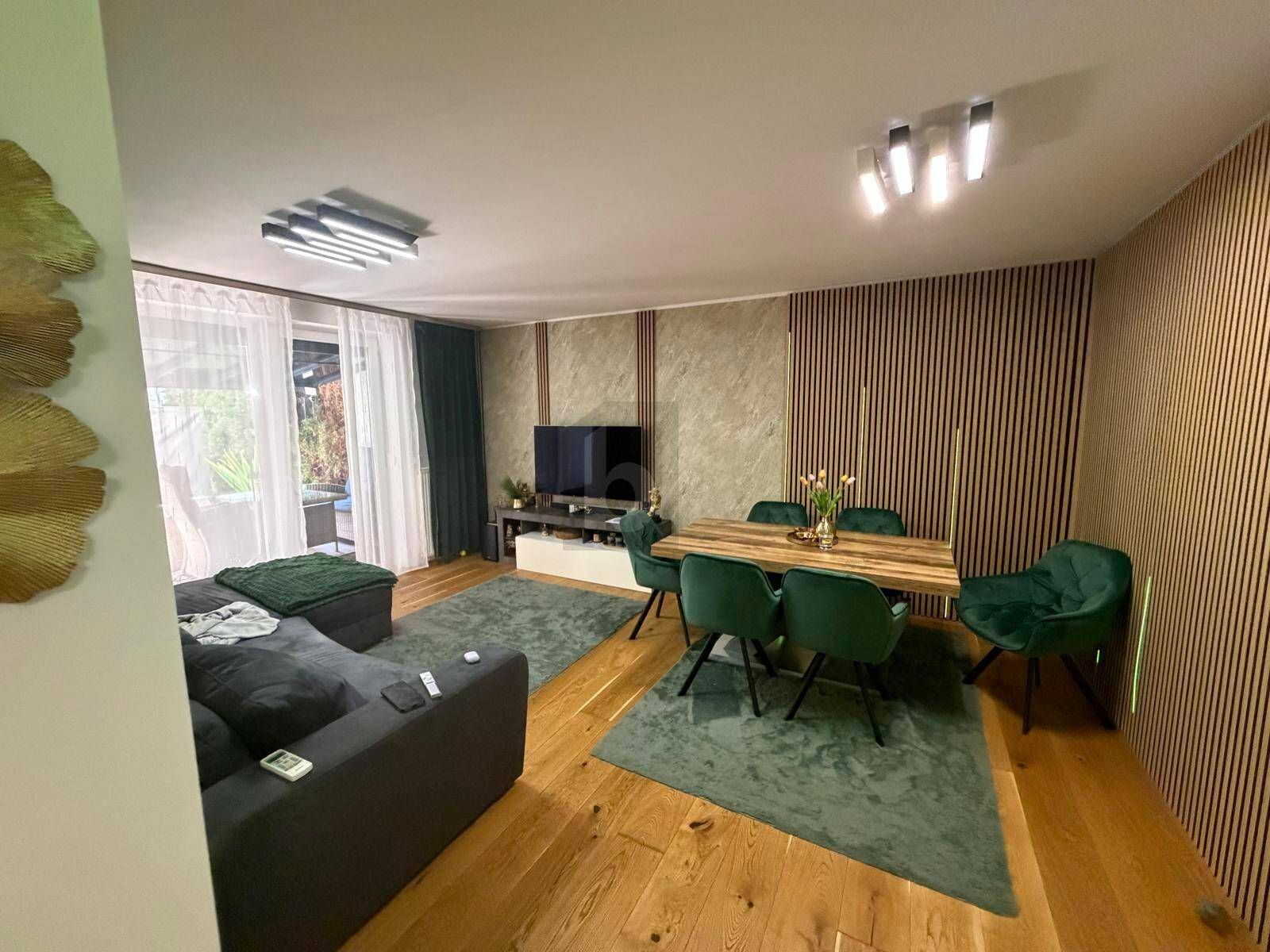Moderner Wohn-Essbereich mit Holzboden, grünen Akzenten und dekorativer Lamellenwand.