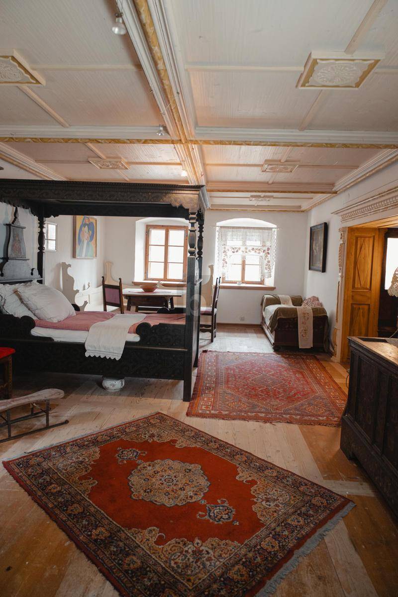 Traditionelles Schlafzimmer mit Himmelbett, Holzboden und verzierten Deckenpaneelen.