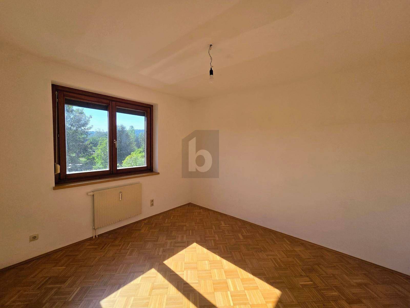 Helles Zimmer mit Parkettboden, großem Fenster und Heizkörper, ideal als Schlafzimmer.