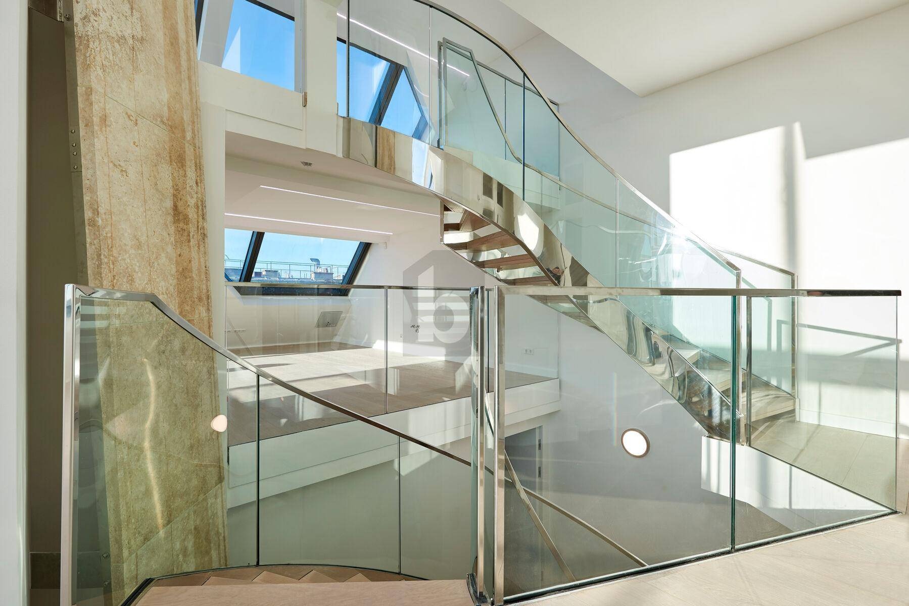 Elegante moderne Treppe mit Glasgeländer und viel Tageslicht.