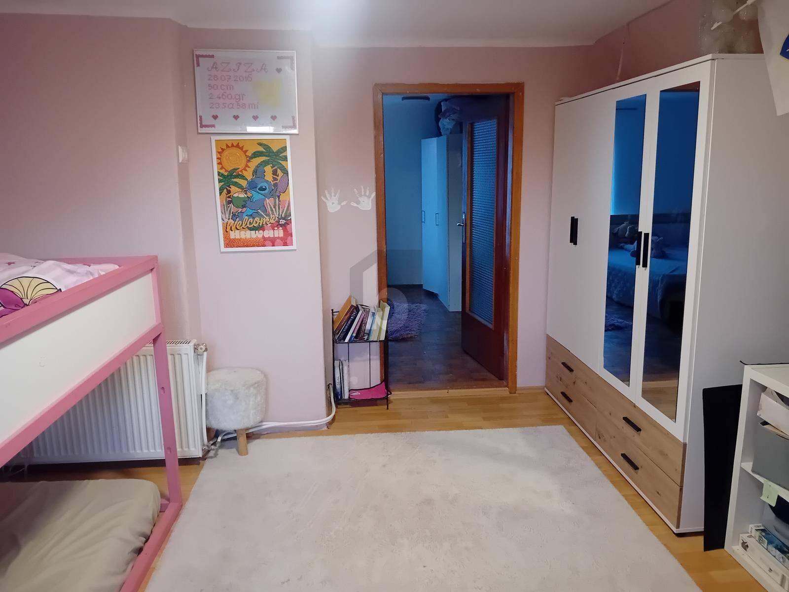 Kinderzimmer mit rosa Wänden, Etagenbett, Spiegelschrank und Teppichboden.