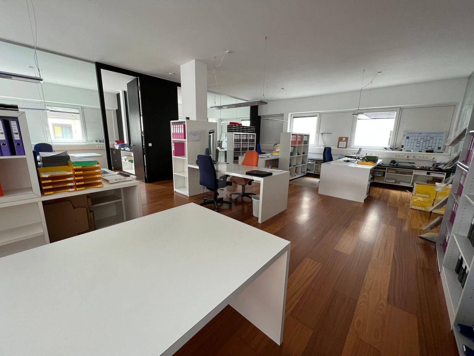 Helles und funktionales Büro mit Holzparkett, weißen Möbeln und ausreichend Stauraum für Akten.