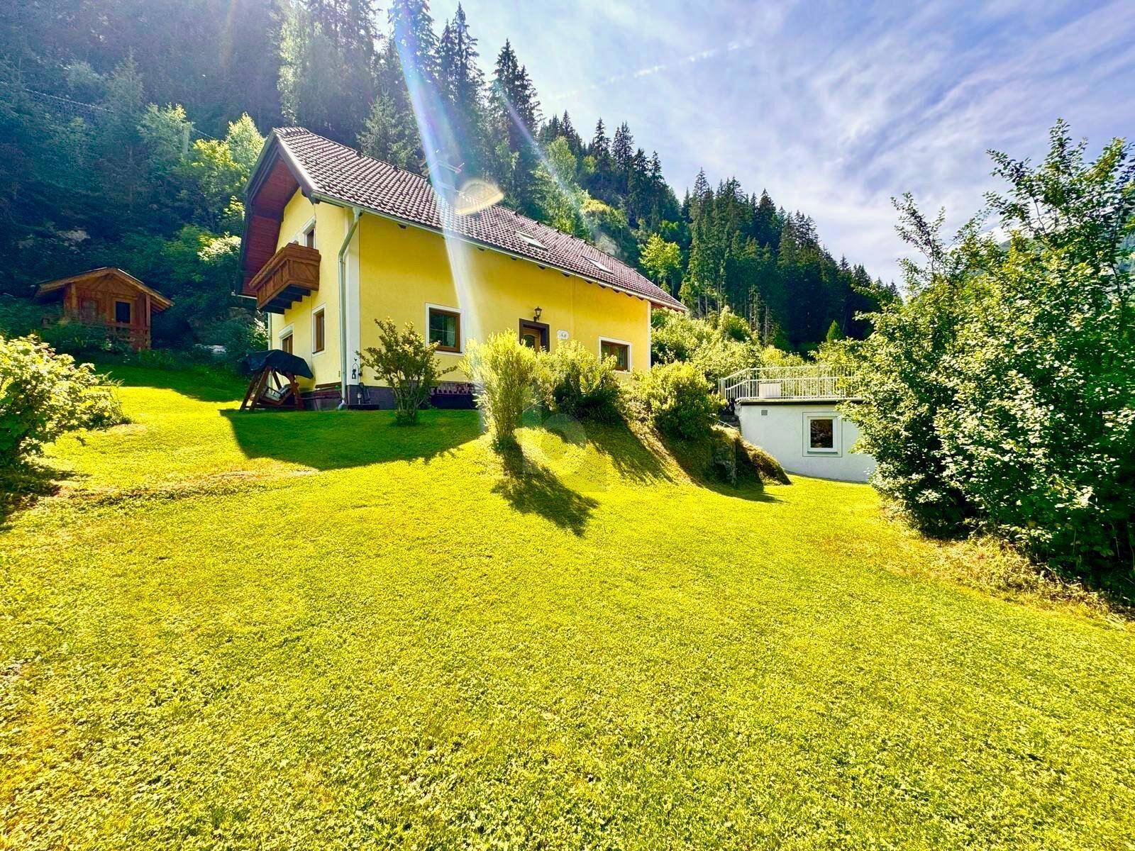 Sonniges gelbes Haus mit großem Garten und Blick auf die umliegende Natur.