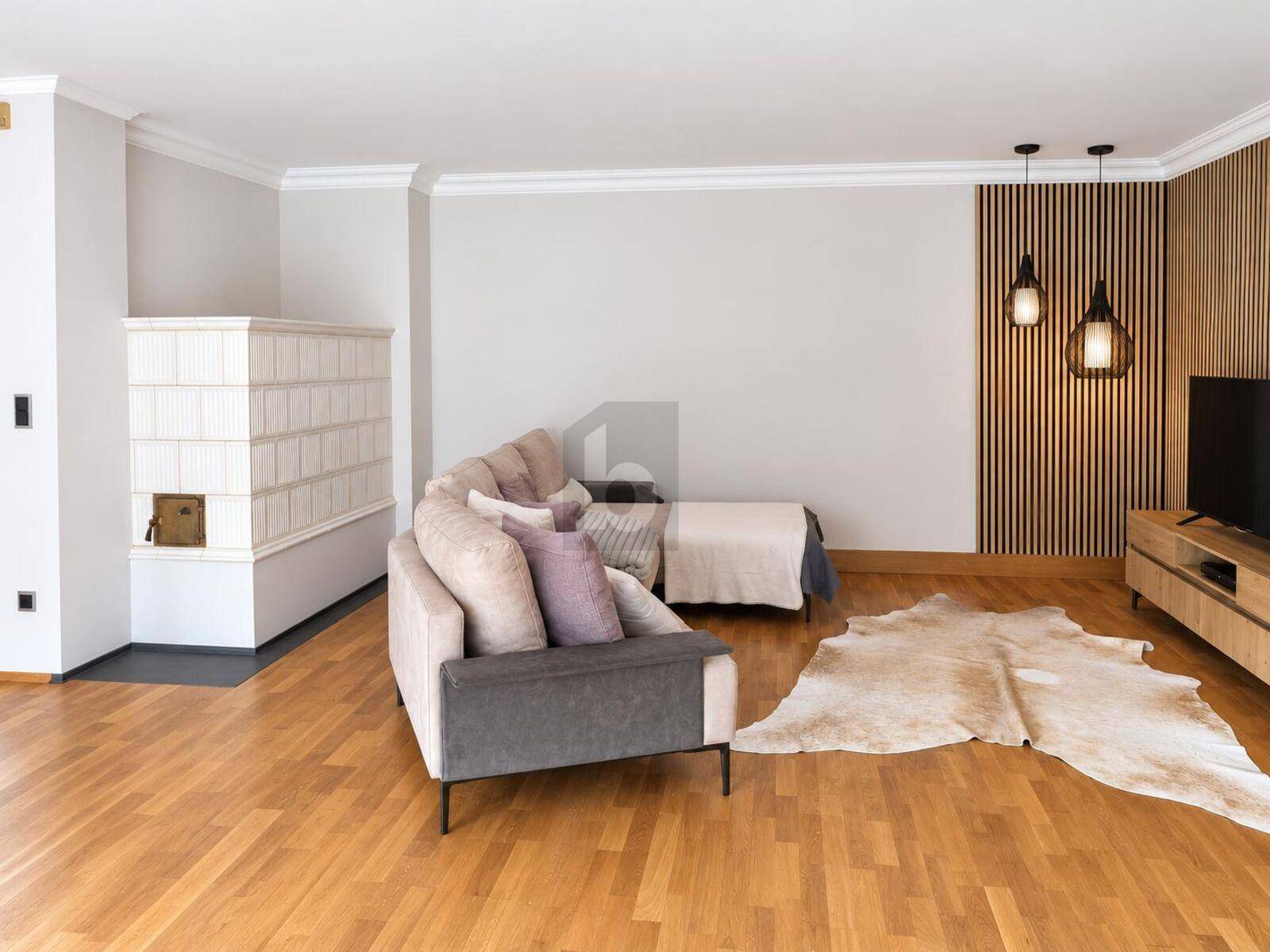 Gemütliches Wohnzimmer mit Holzboden, einem traditionellen Kachelofen und moderner Wandgestaltung.