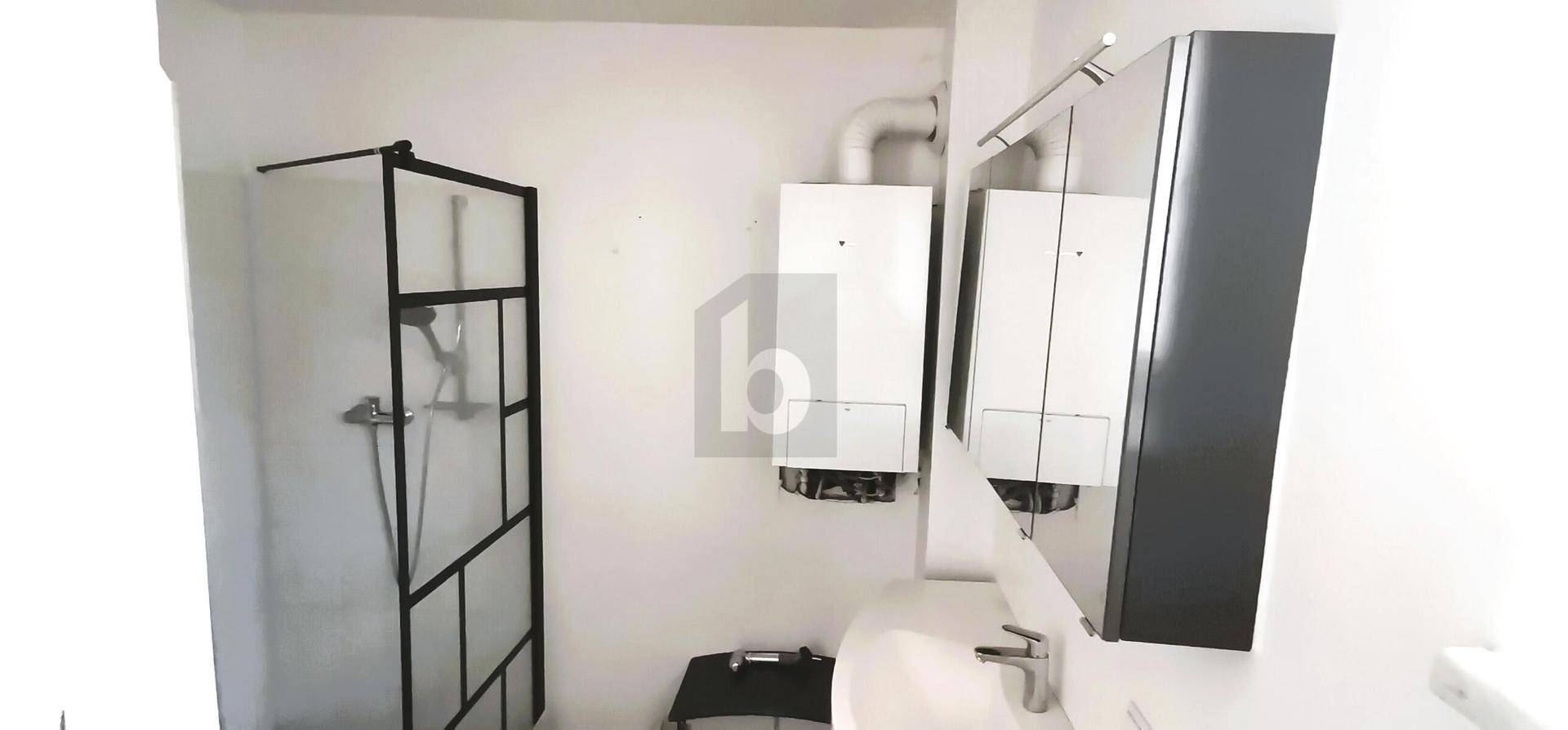 Funktionales Badezimmer mit Duschkabine, Waschbecken und Spiegelschrank.