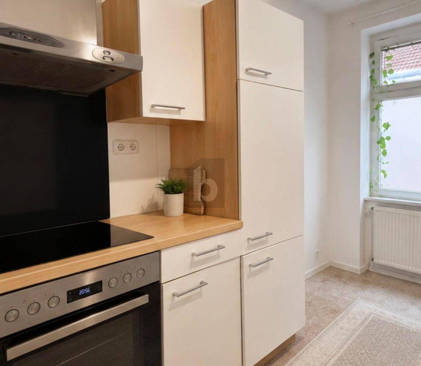 Eine funktionale Küche mit weißen Schränken, Holz-Arbeitsplatten und modernen Einbaugeräten, die einen praktischen Kochbereich bietet.