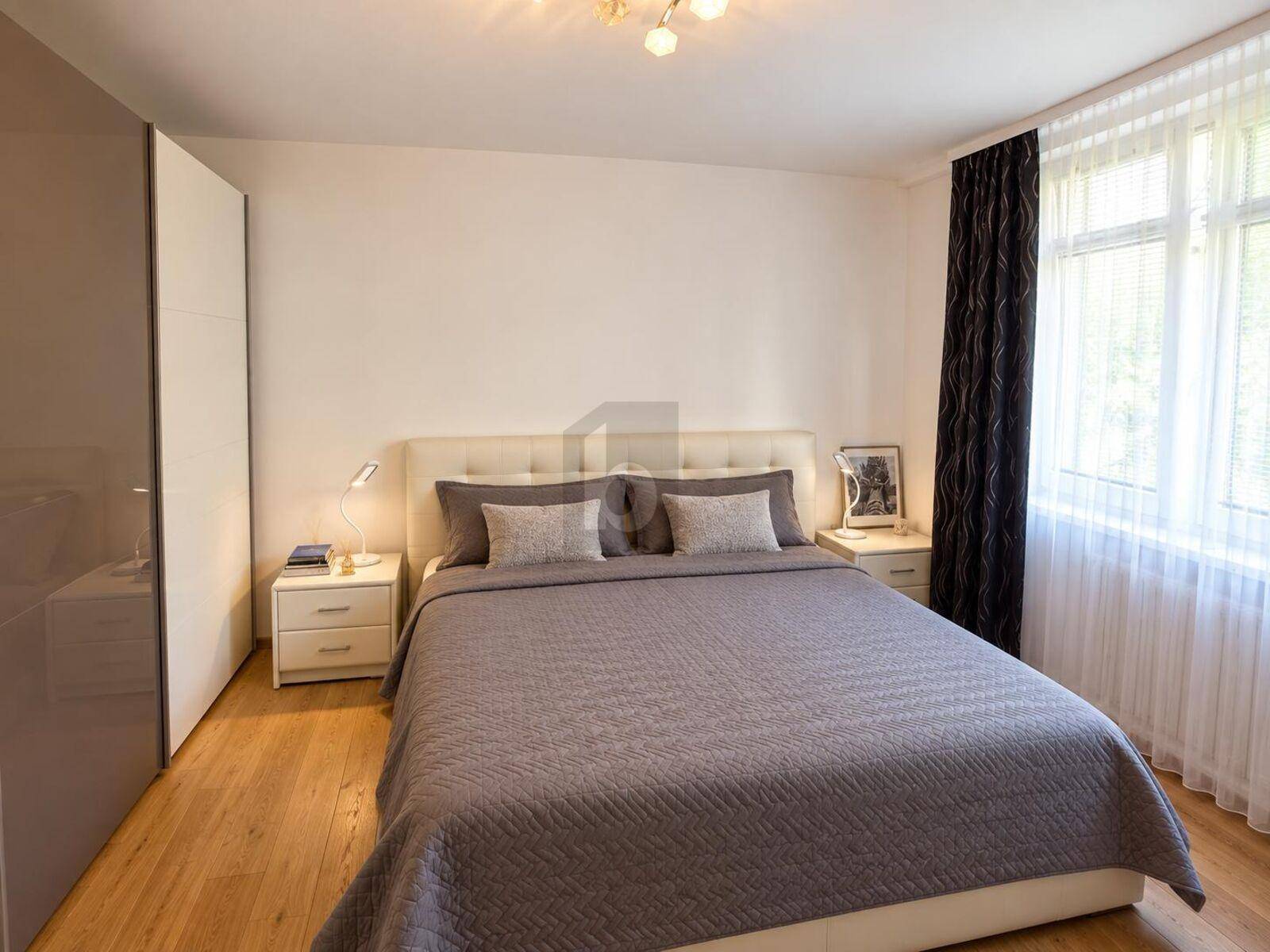 Helles Schlafzimmer mit Doppelbett, Nachttischen und großem Kleiderschrank.