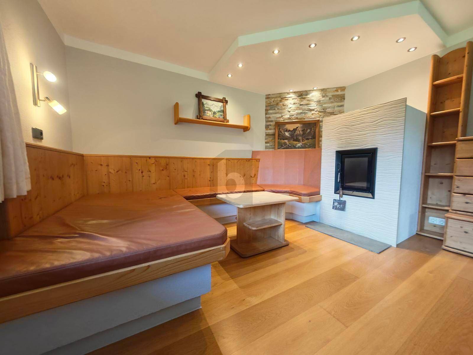 Gemütlicher Wohn- und Essbereich im alpinen Stil mit Holzbänken, Kamin und Holzboden.
