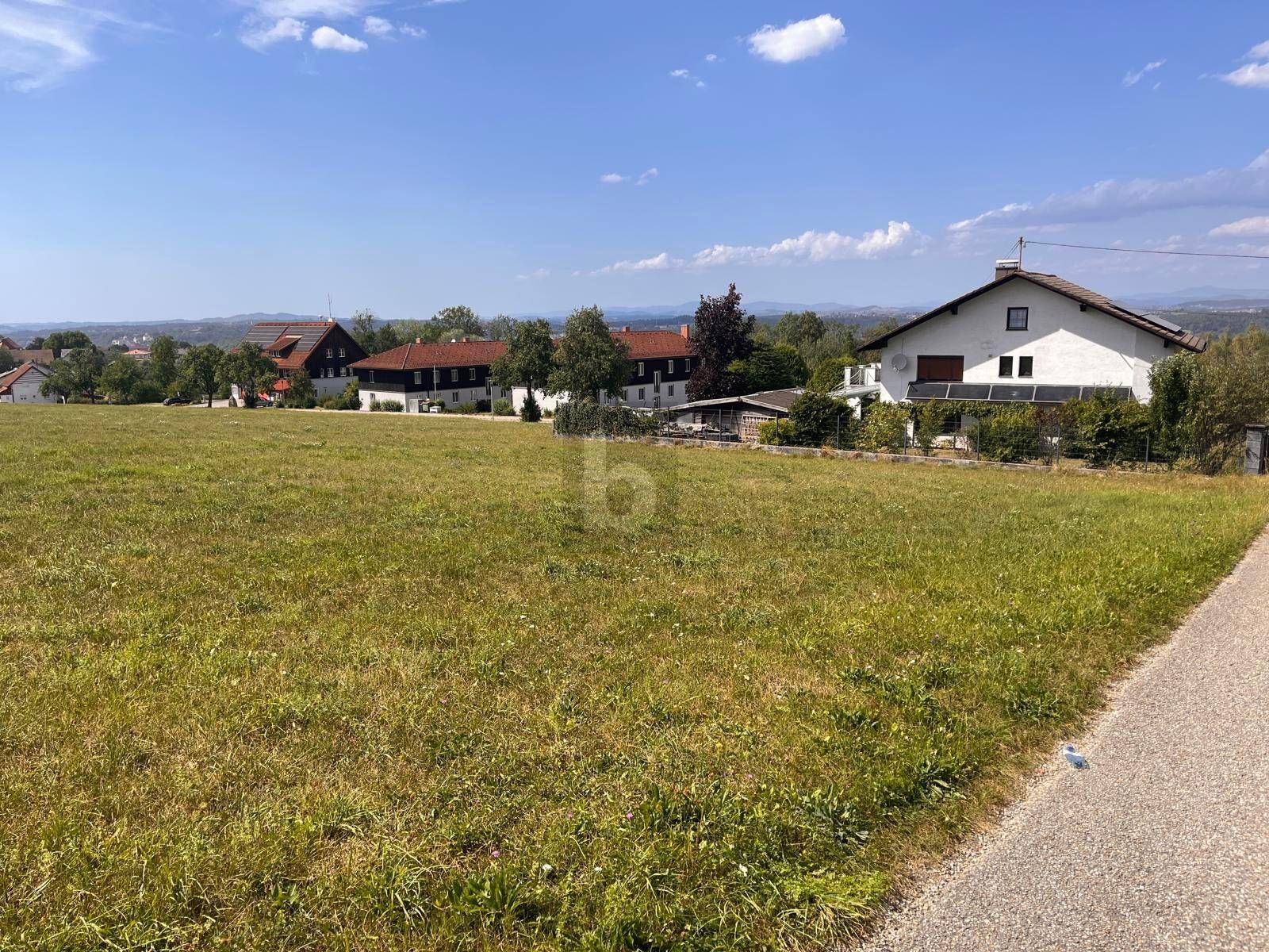Großes grünes Grundstück mit Fernblick auf die Landschaft und Häuser in der Umgebung.