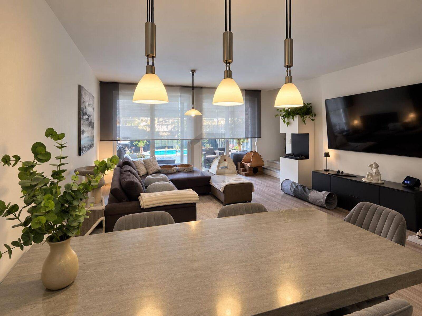 Offener Wohn- und Essbereich mit modernem Design und Blick auf den Außenbereich mit Pool.