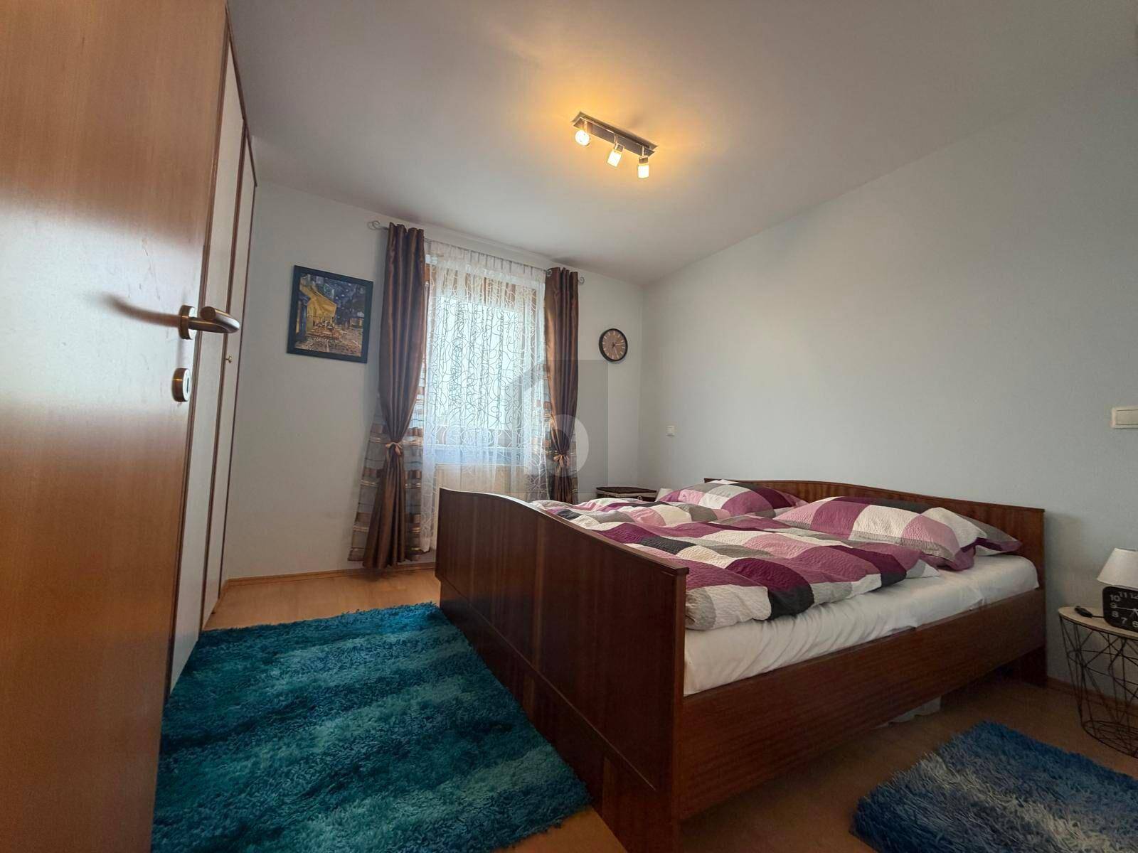 Schlafzimmer mit Holzbett, Kleiderschrank und Fenster mit Vorhängen für Privatsphäre.