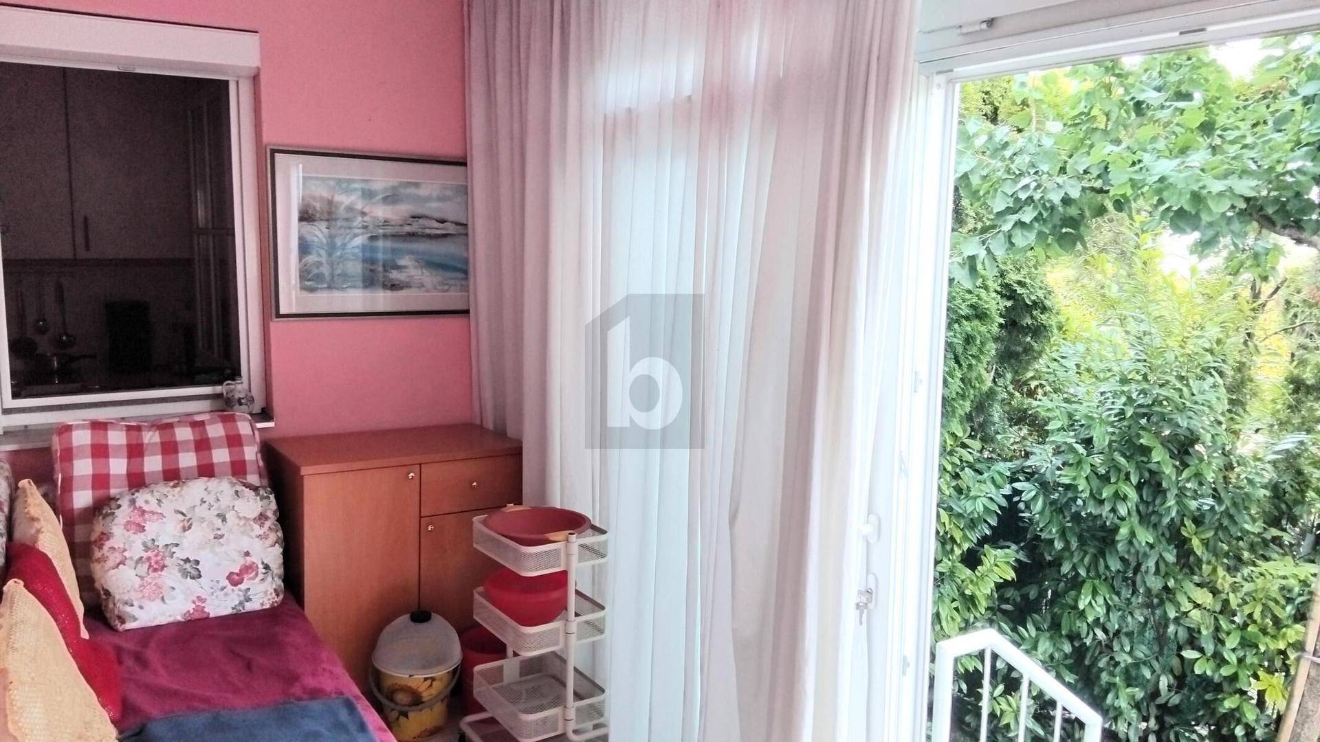 Heller Innenraum mit rosa Wänden, einem Sofa und Blick ins Grüne durch die große Glastür.