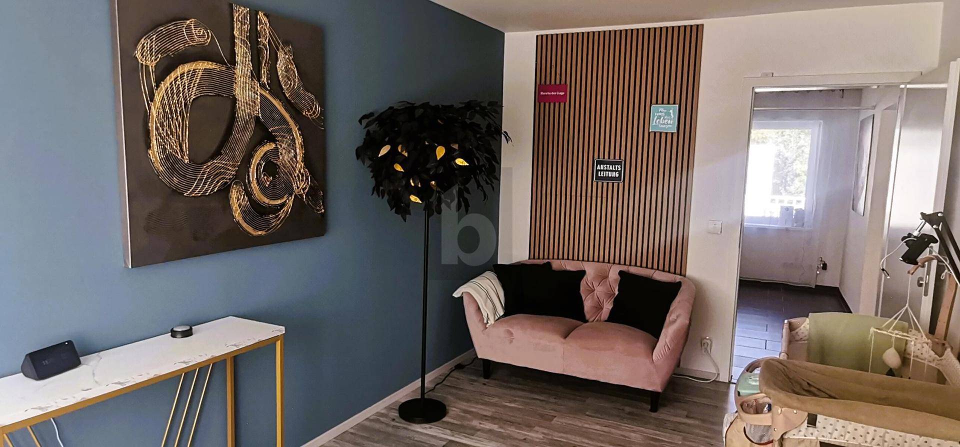 Wohnzimmer mit blauer Wand, rosa Sofa und dekorativer Holzvertäfelung.