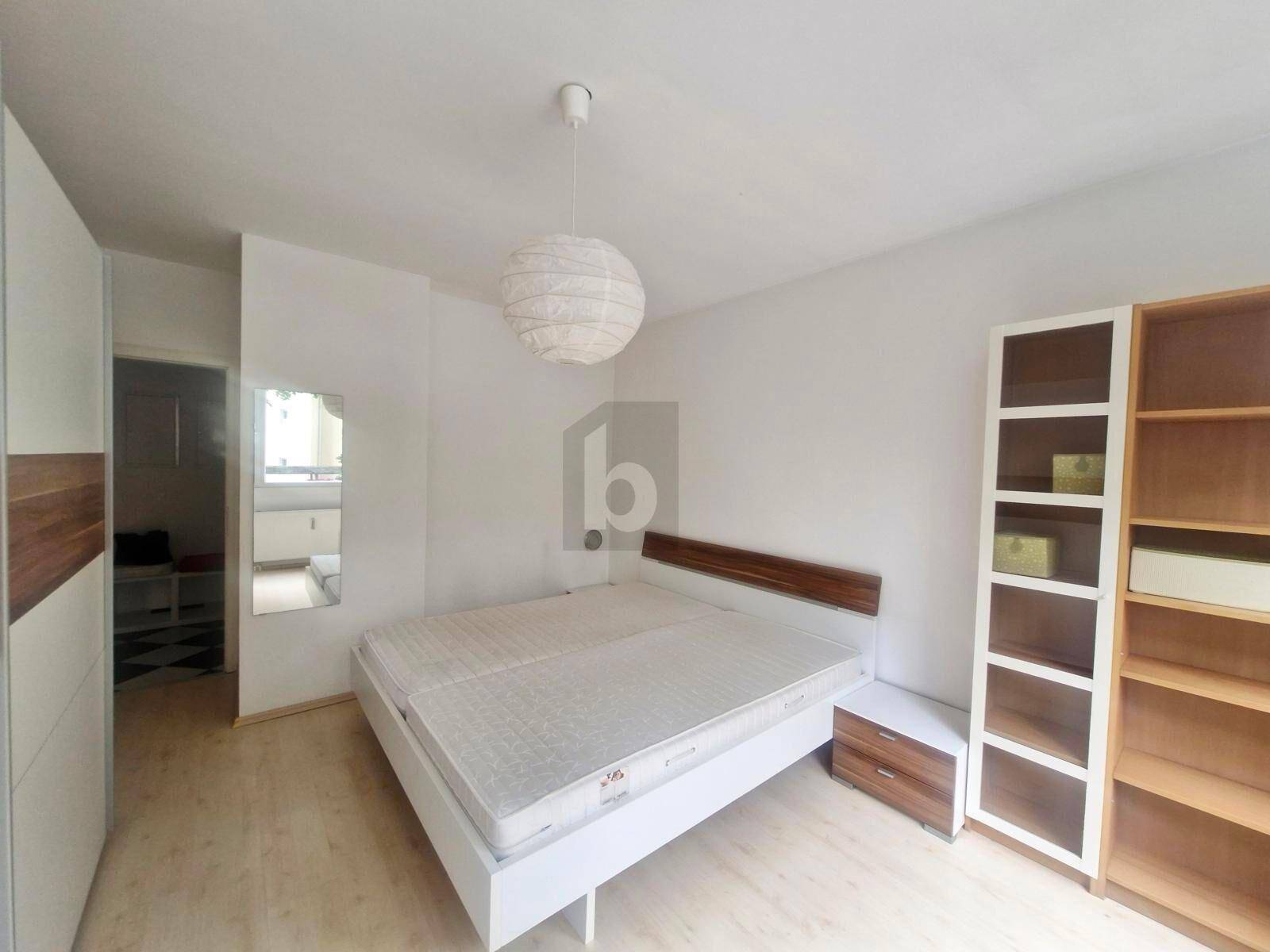 Helles Schlafzimmer mit Doppelbett, Kleiderschrank und Nachttisch.