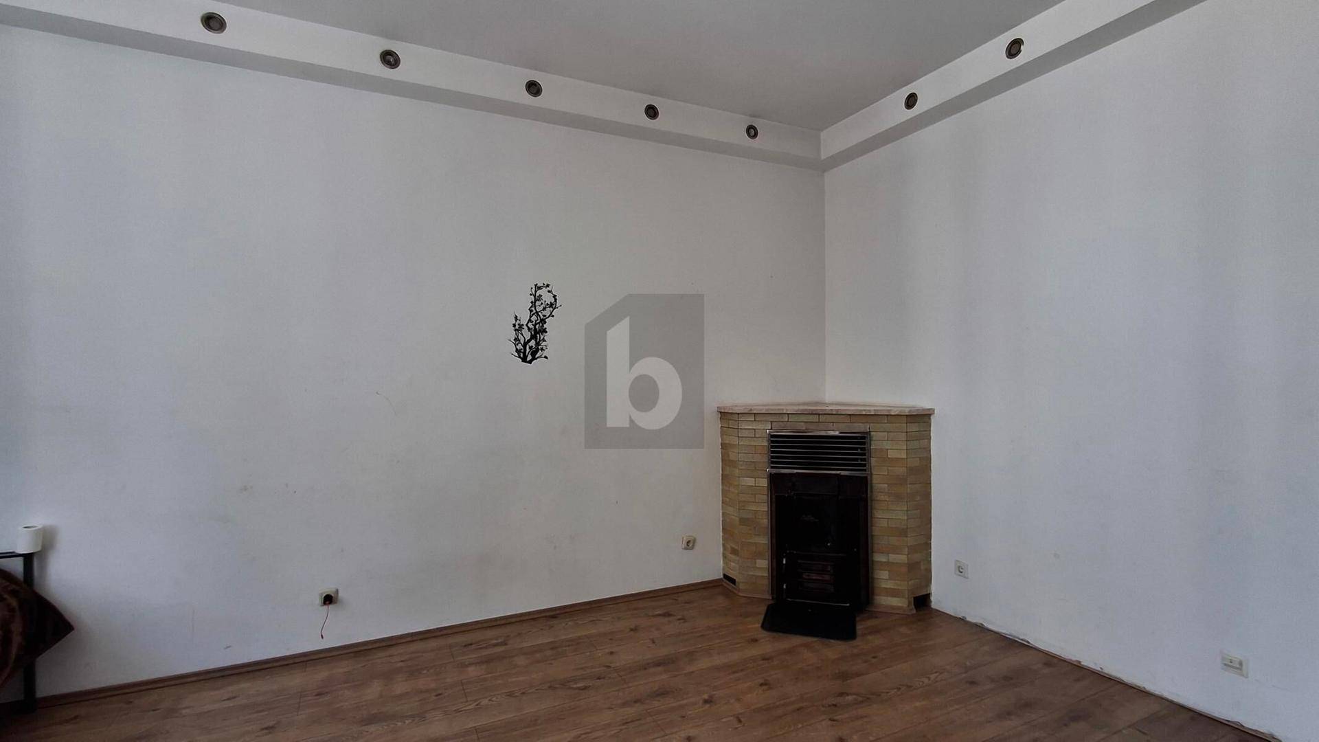 Geräumiges Zimmer mit Holzboden und einem Eckkamin, ideal für gemütliche Abende.