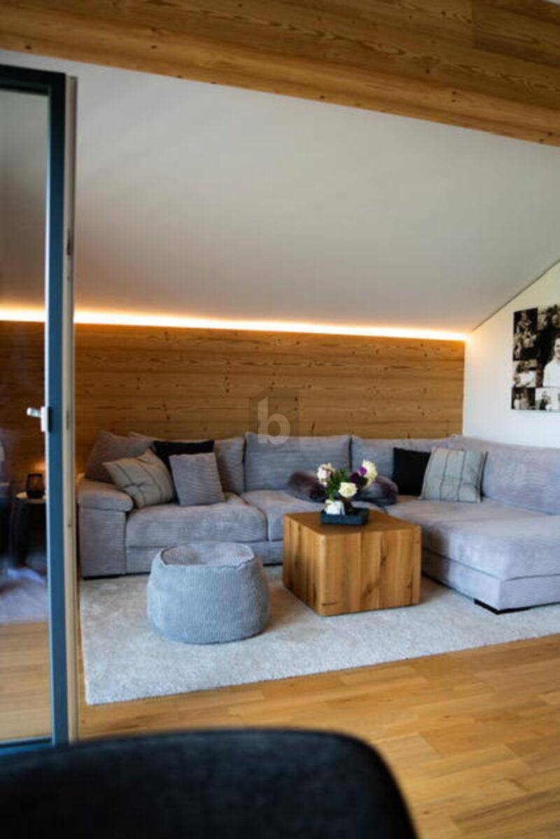Gemütliches Wohnzimmer mit großem Ecksofa, Holztisch und indirekter Beleuchtung.