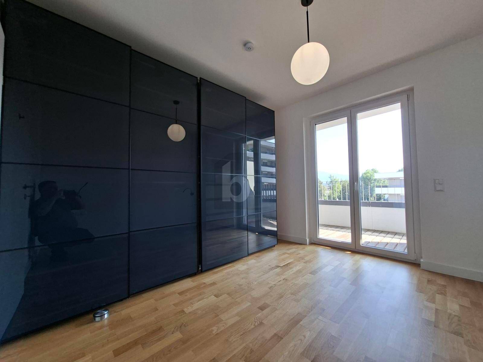 Schlafzimmer mit großem Einbauschrank, Holzparkett und direktem Zugang zu einem Balkon.