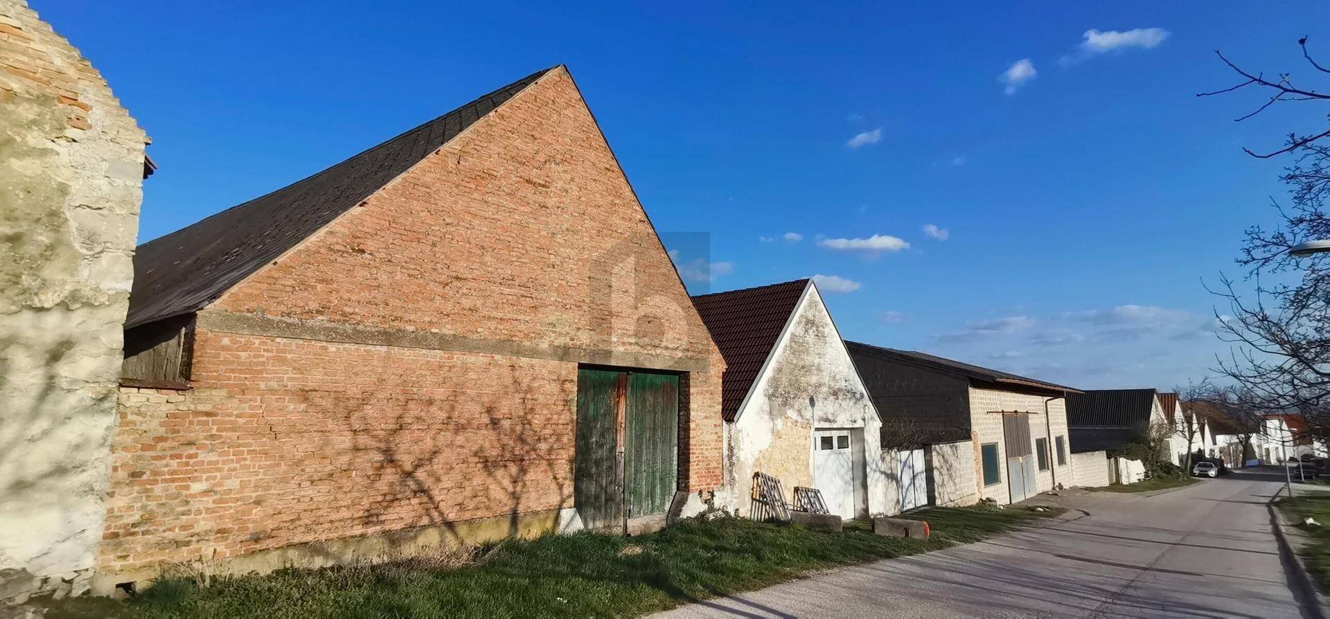 Reihe ländlicher Backsteingebäude entlang einer Straße unter strahlend blauem Himmel.